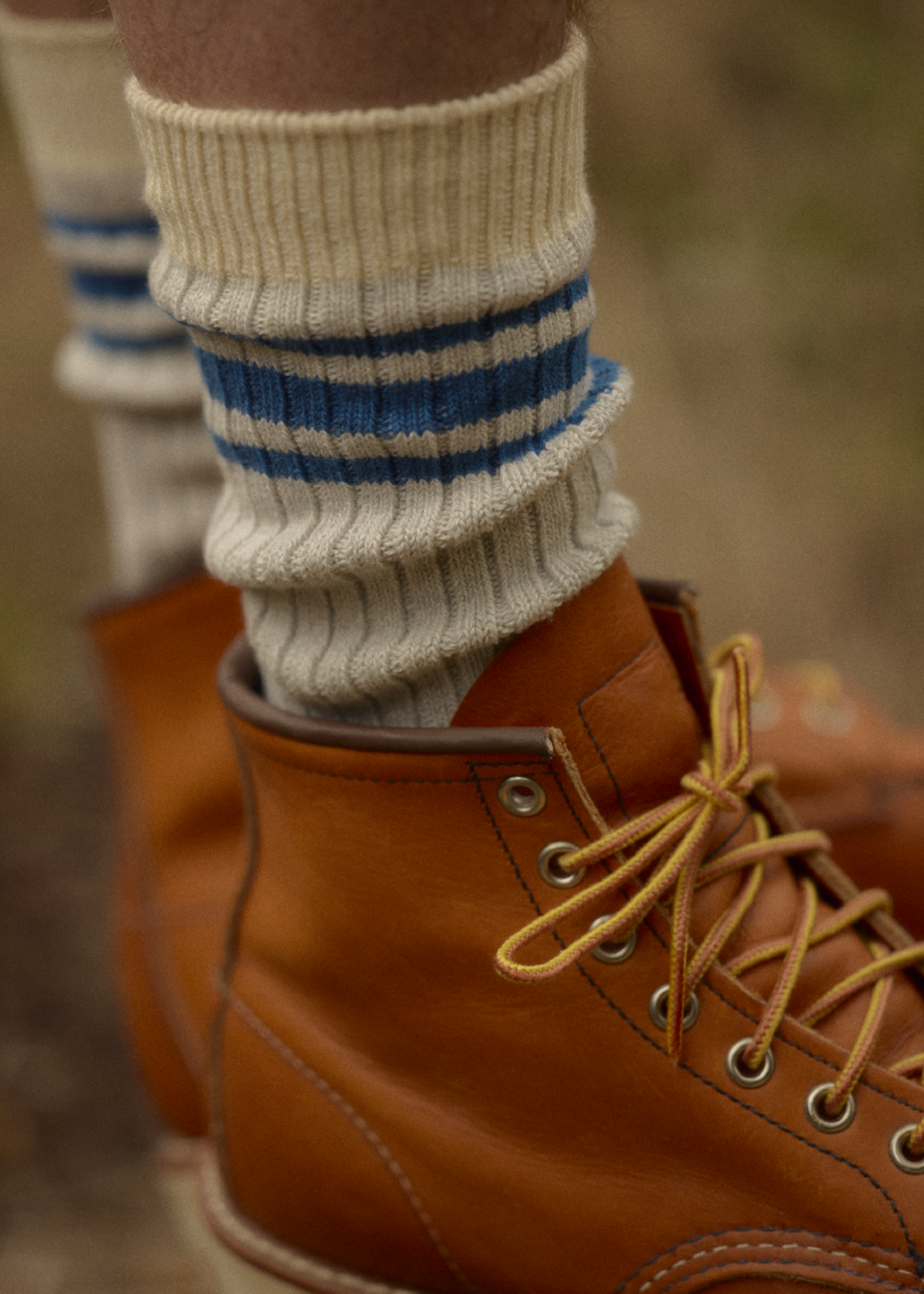 Close-up of Saturday socks styled with brown leather boots outdoors.