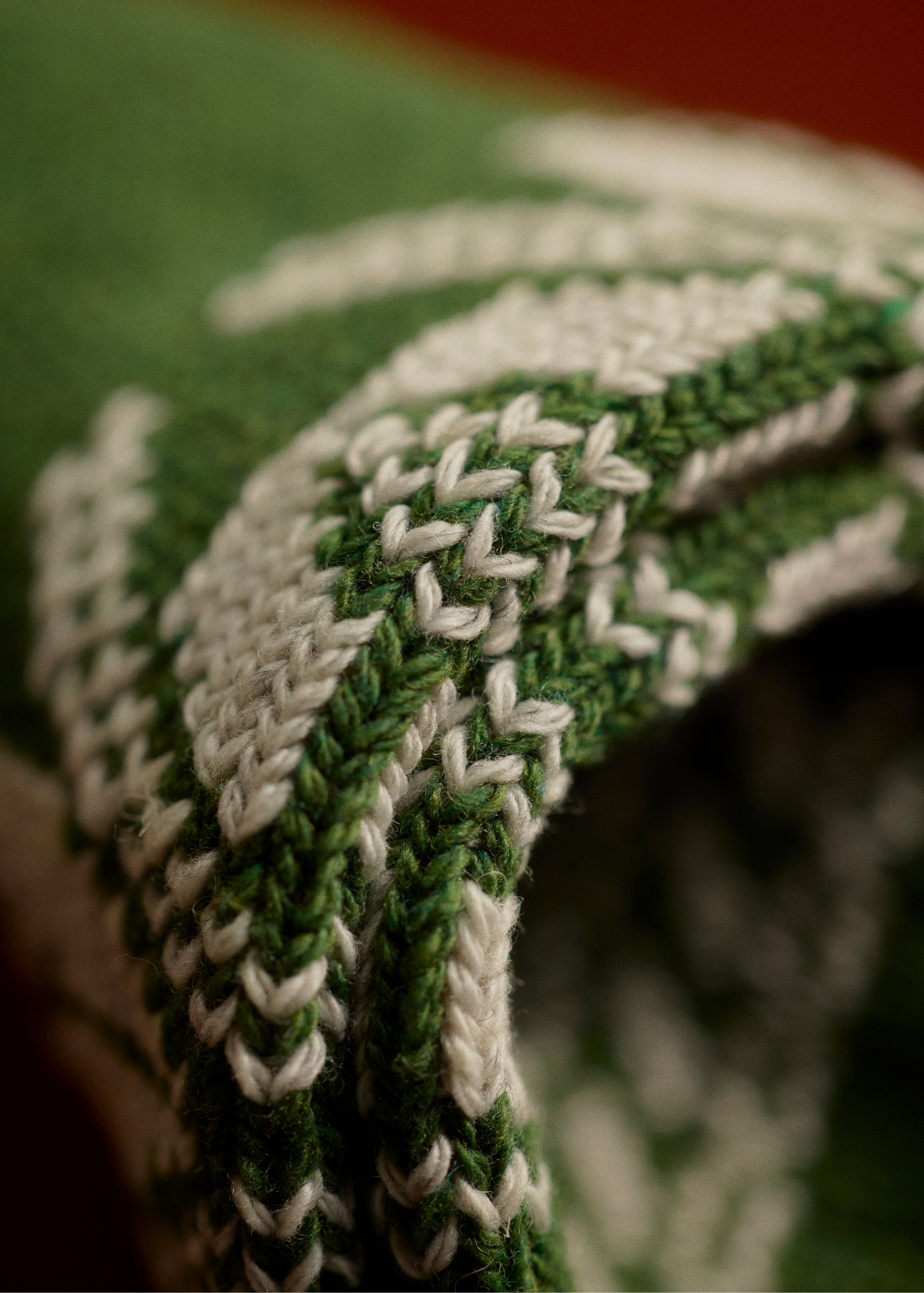 Close-up of a green and white knitted fabric with a herringbone pattern.